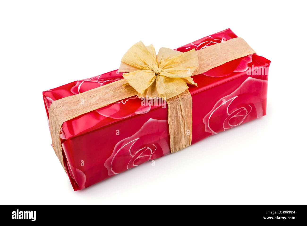 Confezione regalo avvolto in una rosa rossa cellophane, decorata con rafia ecru nastro e bow isolati su sfondo bianco Foto Stock