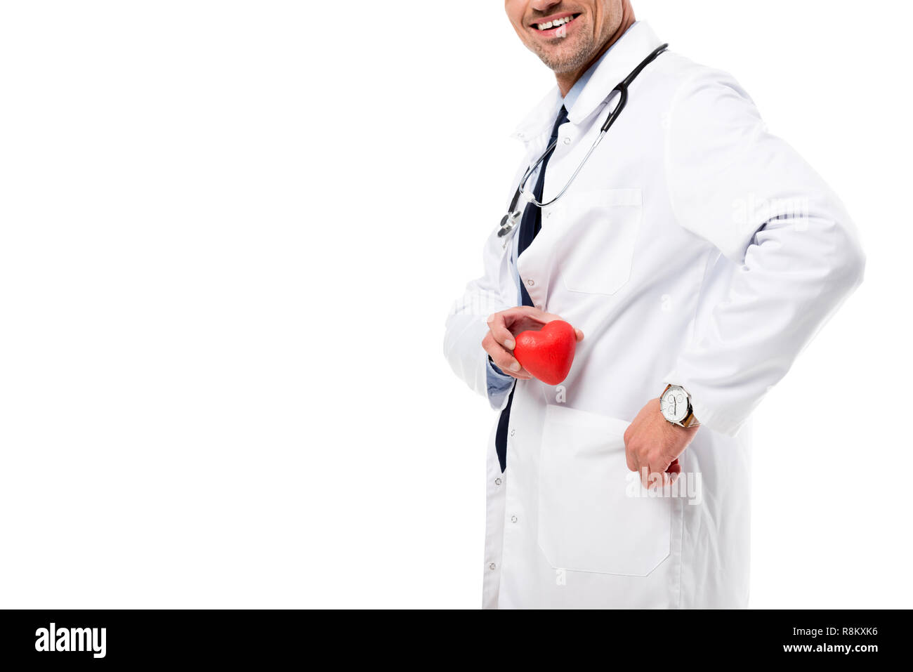 Vista ritagliata di sorridere medico in camice bianco con uno stetoscopio azienda modello cuore in mano isolato su bianco, cuore il concetto di assistenza sanitaria Foto Stock