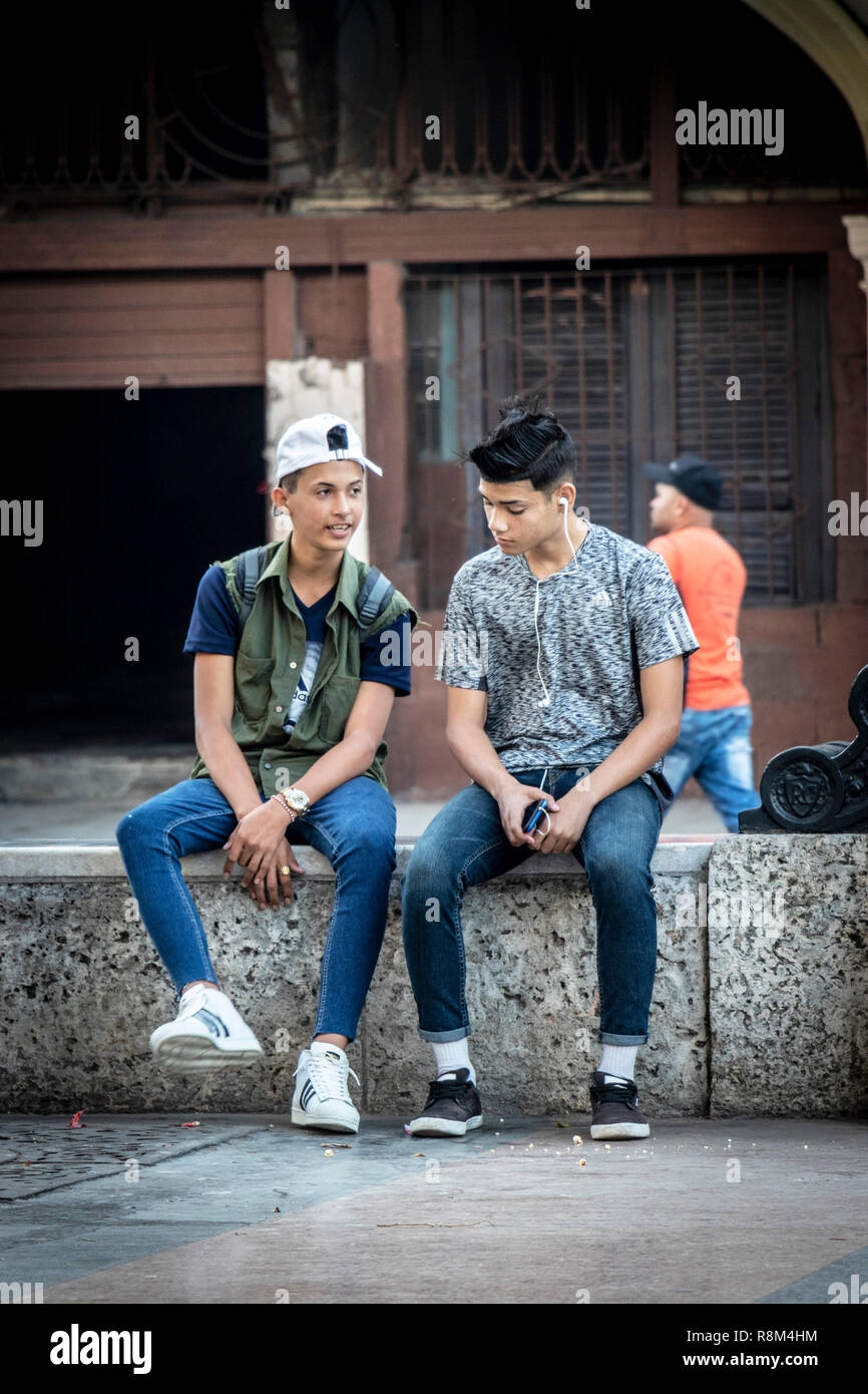 Due cool latino ragazzi adolescenti a sedersi su una parete in Havana Cuba Foto Stock