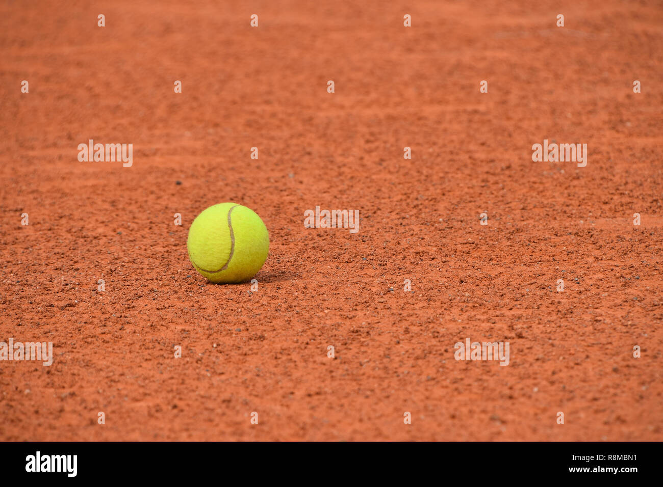 Chiudere un feltro giallo palla da tennis su rosso marrone la massa di argilla corte, basso angolo di visione Foto Stock