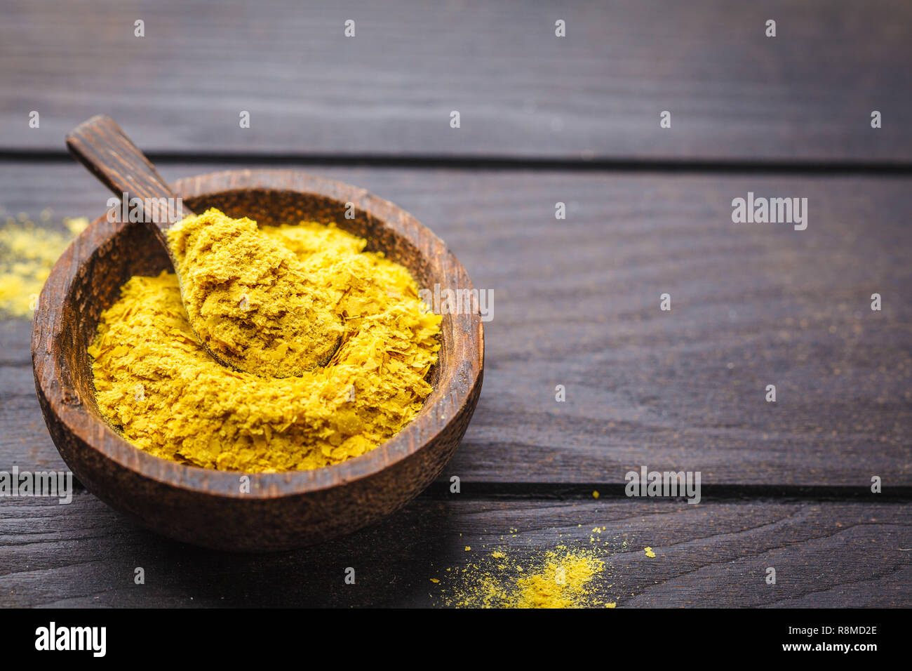 Il lievito nutrizionale in una ciotola di legno, copia spazio, sfondo scuro, copia dello spazio. Sano cibo vegan concetto. Foto Stock