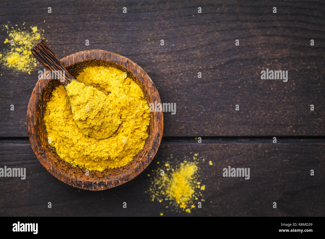 Il lievito nutrizionale in una ciotola di legno, copia spazio, sfondo scuro, copia dello spazio. Sano cibo vegan concetto. Foto Stock