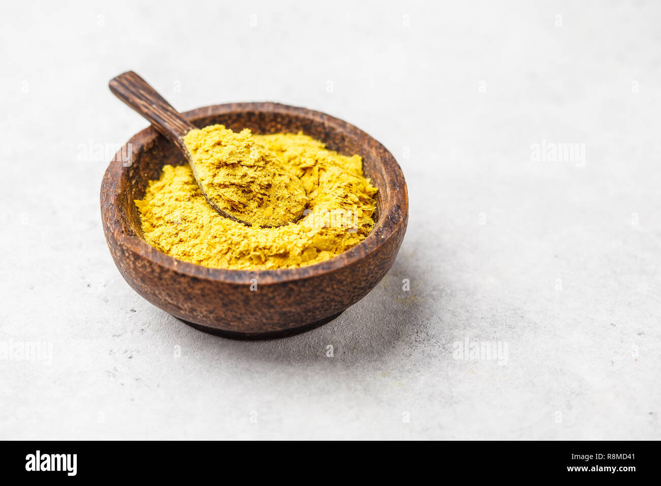 Il lievito nutrizionale in una ciotola di legno, copia spazio, sfondo bianco, copia dello spazio. Sano cibo vegan concetto. Foto Stock