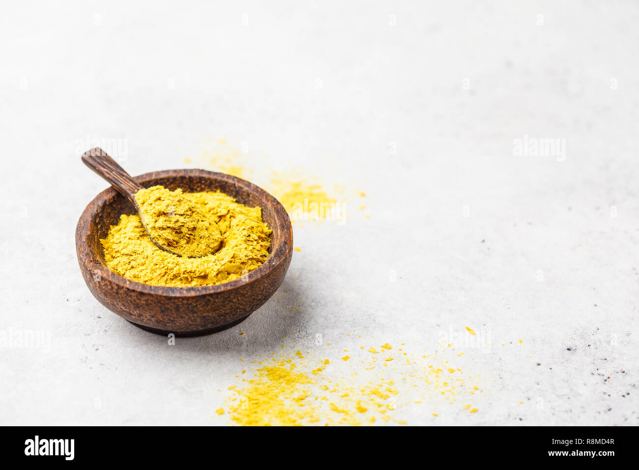 Il lievito nutrizionale in una ciotola di legno, copia spazio, sfondo bianco, copia dello spazio. Sano cibo vegan concetto. Foto Stock