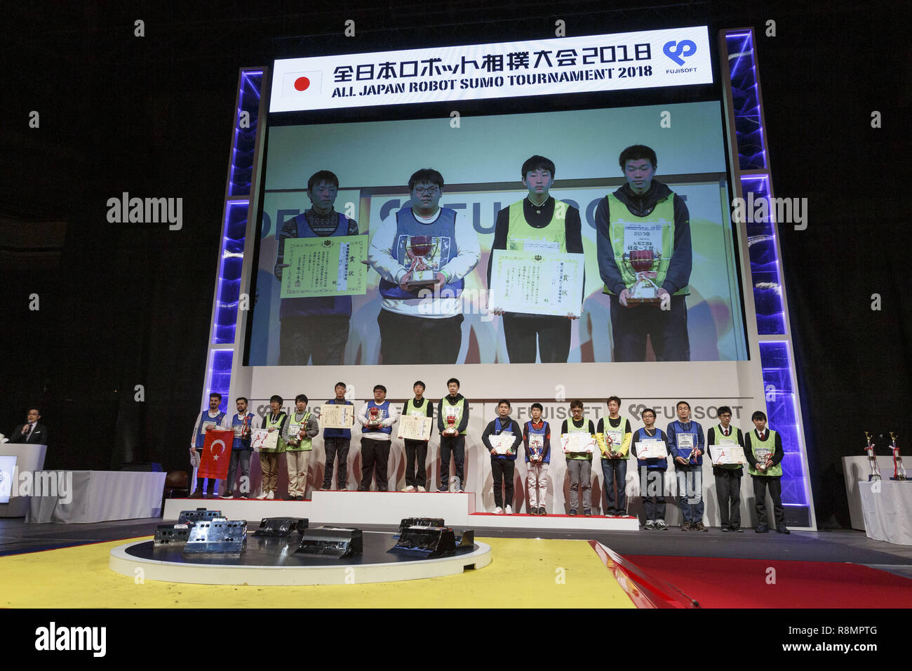 Tokyo, Giappone. Xvi Dec, 2018. I vincitori per la ''tutto il Giappone Robot Torneo di Sumo 2018'' rappresentare per le telecamere al Ryogoku Kokugikan sumo hall. Il torneo annuale invita la parte superiore nella classifica vincitori dal Giappone e 19 paesi diversi per vedere che il robot sarebbe il più forte. Vi erano due divisioni, una per radio controlled "" sumo robot"" e l' altra per i lottatori di autonoma. Secondo le regole del robot lottatore perde quando il loro robot è forzato fuori dell'anello di sumo. Credito: Rodrigo Reyes Marin/ZUMA filo/Alamy Live News Foto Stock