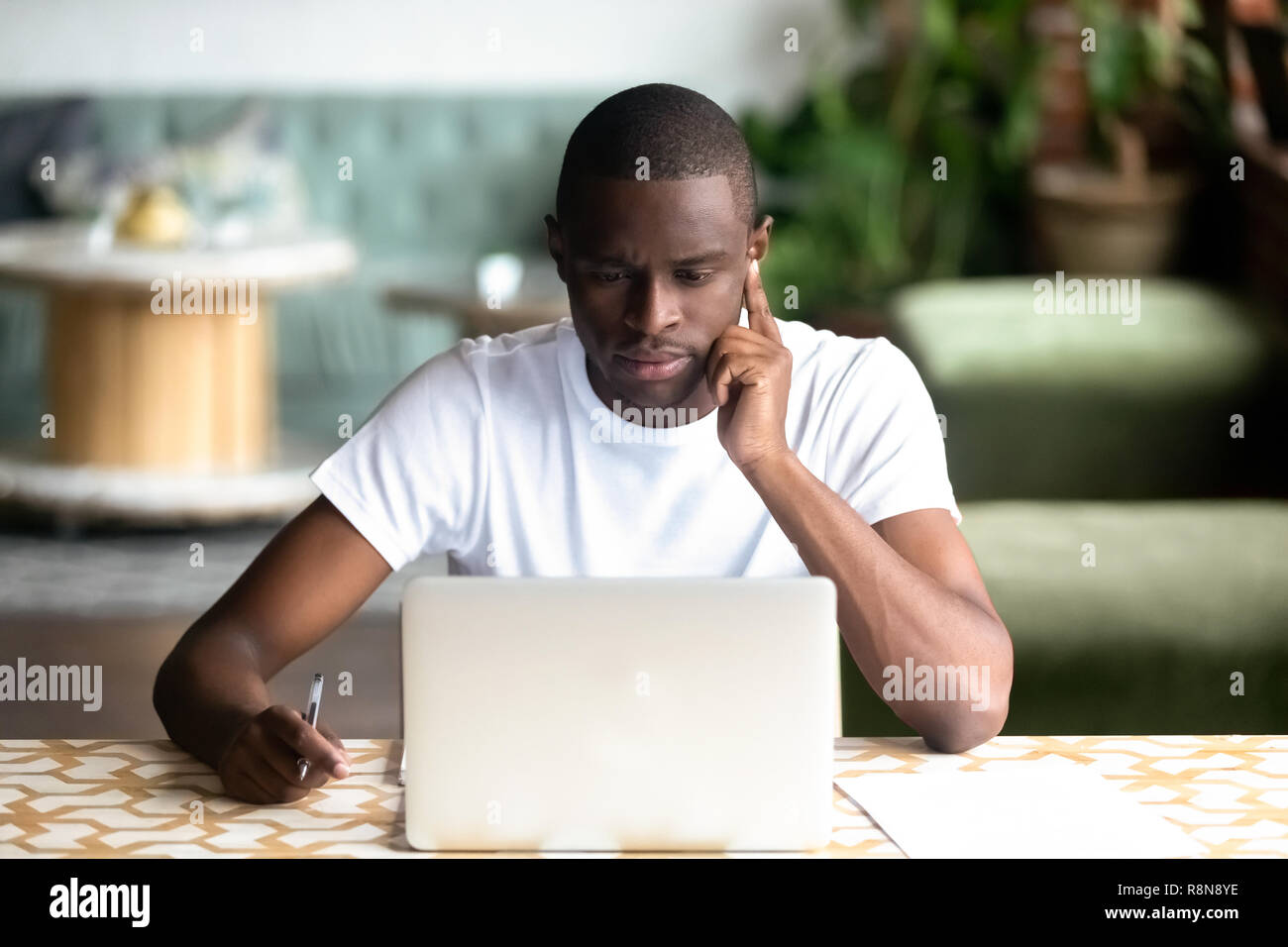 Focalizzato African American uomo utilizzando laptop in cafe Foto Stock