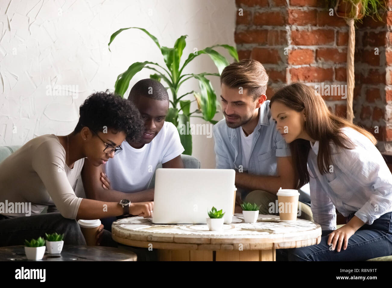 Focalizzato americano africano donna con gli amici utilizzando laptop Foto Stock