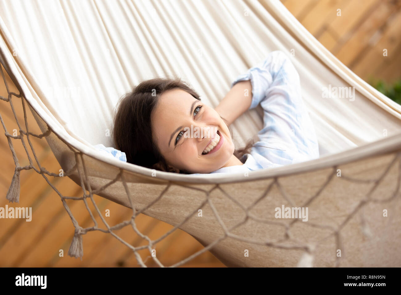 Sorridenti giovane donna giacente in amaca cercando in base alla distanza Foto Stock