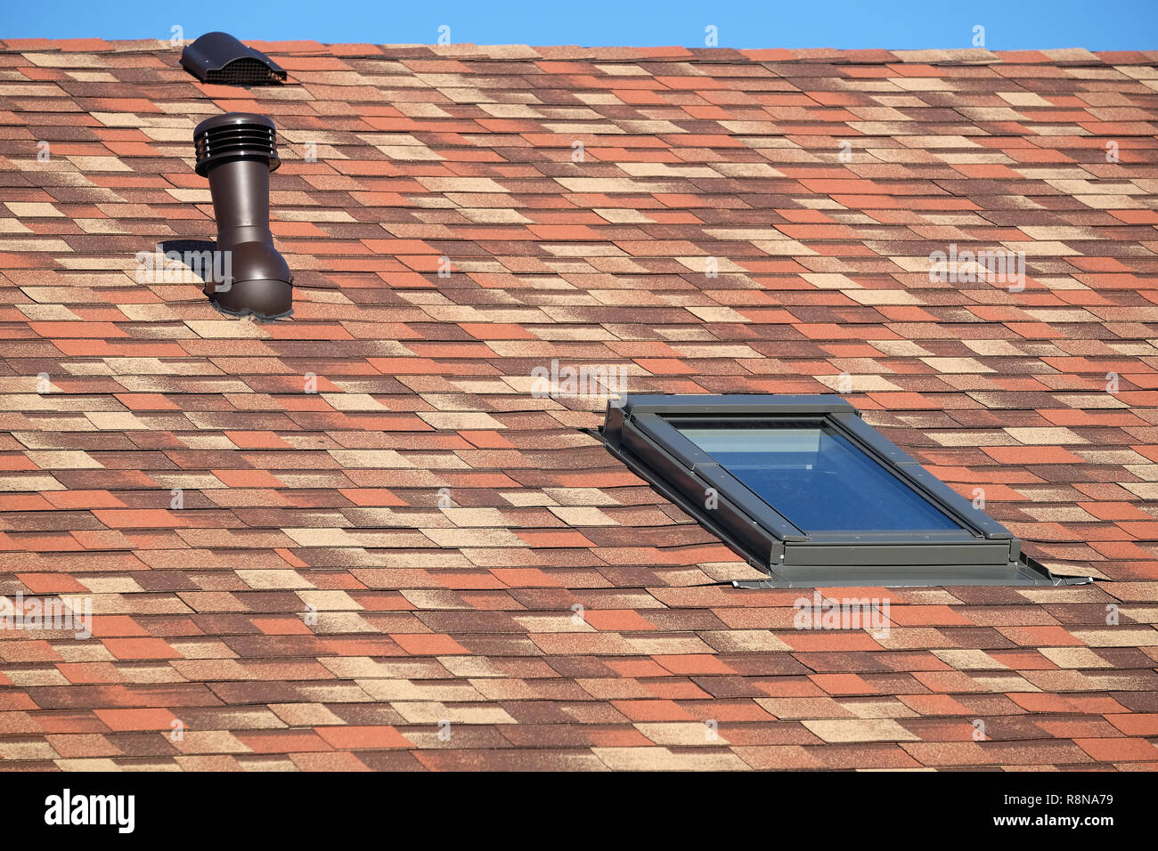 Vetro del tetto e il tubo di ventilazione sulla casa residenziale coperto con motley soft shingles vista ravvicinata Foto Stock
