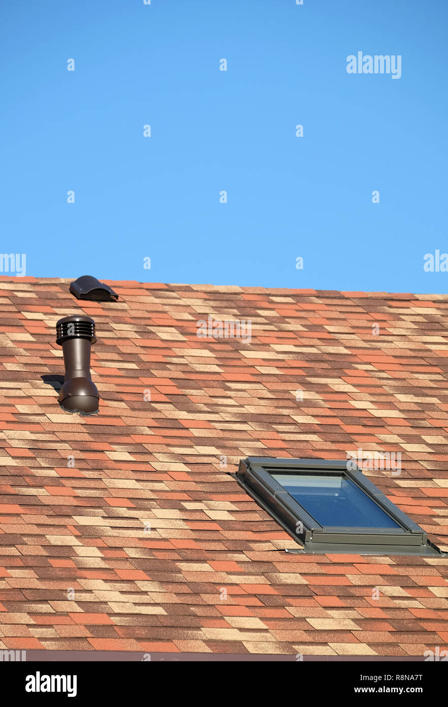 Vetro del tetto e il tubo di ventilazione sulla casa residenziale coperto con motley soft shingles vista ravvicinata Foto Stock