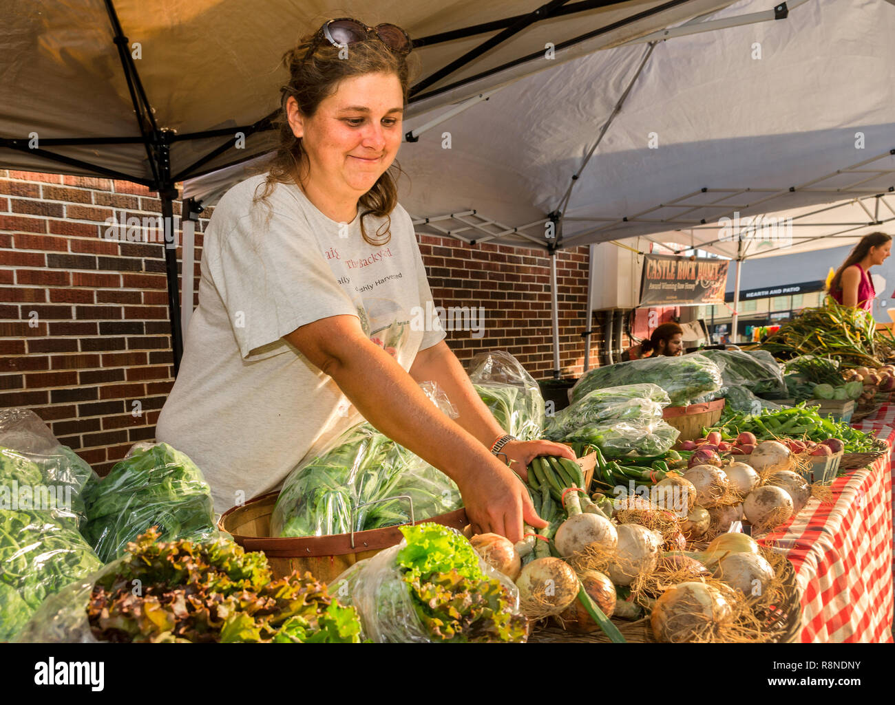 Loganville agricoltore Lynn Teddlie organizza la produzione presso il suo stand vendor durante il Mercato degli Agricoltori in Tucker, Georgia. Foto Stock