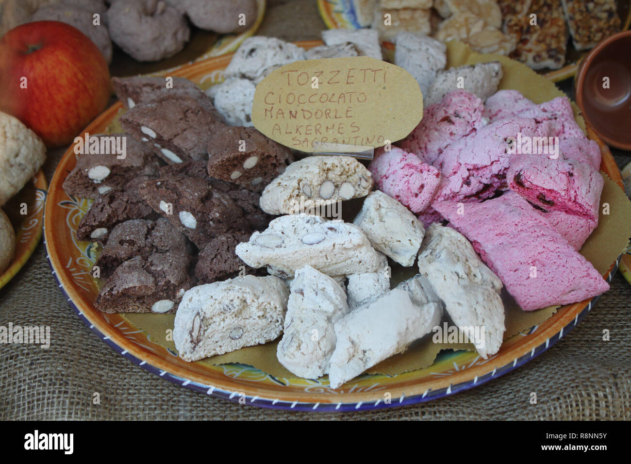 Tradizionale Italiana Tozzetti biscotti visualizzati in una panetteria. Testo in italiano descrive i diversi sapori dei biscotti. Foto Stock