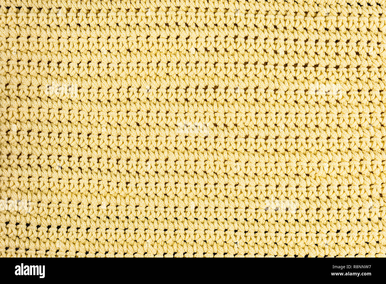 Real, giallo Maglia frammento di tessuto fatto di fibre di lana di sfondo a trama, con delicate pattern. Foto Stock