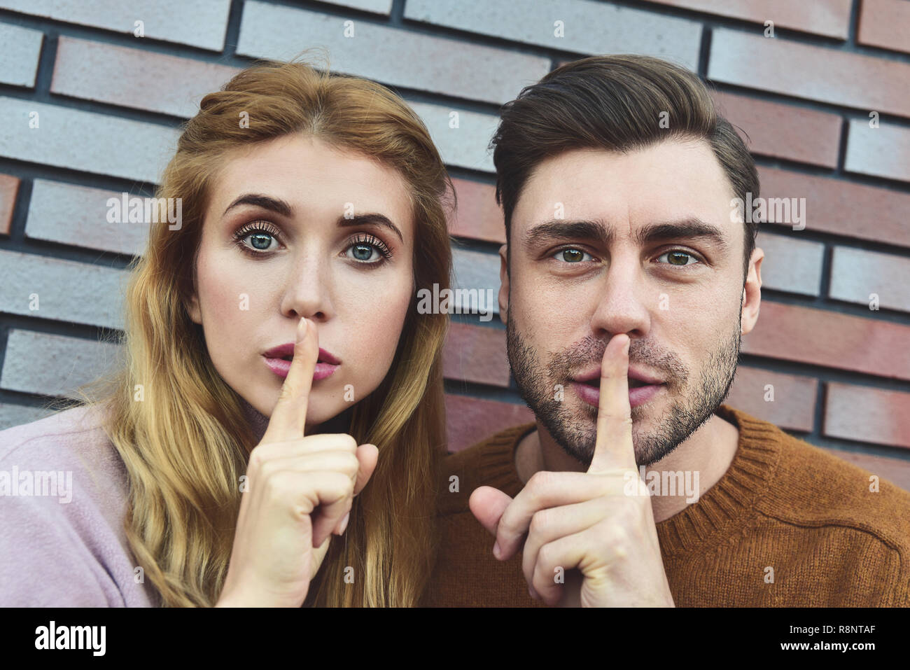 Attraente caucasico giovane giovane bella donna e uomo bello per chiedere silenzio, mantenendo le dita indice sulle loro labbra, dicendo di shh. Persone, relazioni Foto Stock