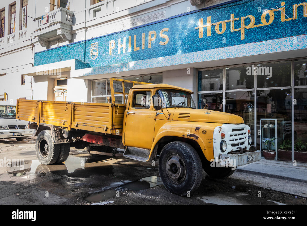 Classico camion giallo americano degli anni '50 di fronte al vecchio cartello Mosaic Philips Hotpoint a l'Avana, Cuba, Foto Stock