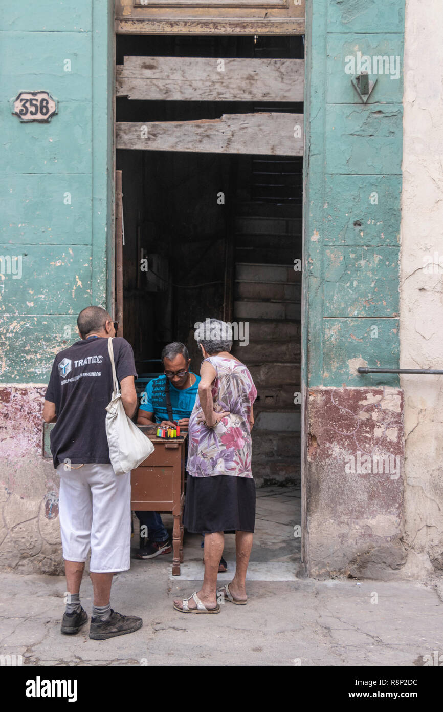Vecchi residenti acquisto di merci al negozio in parete in Havana Cuba Foto Stock