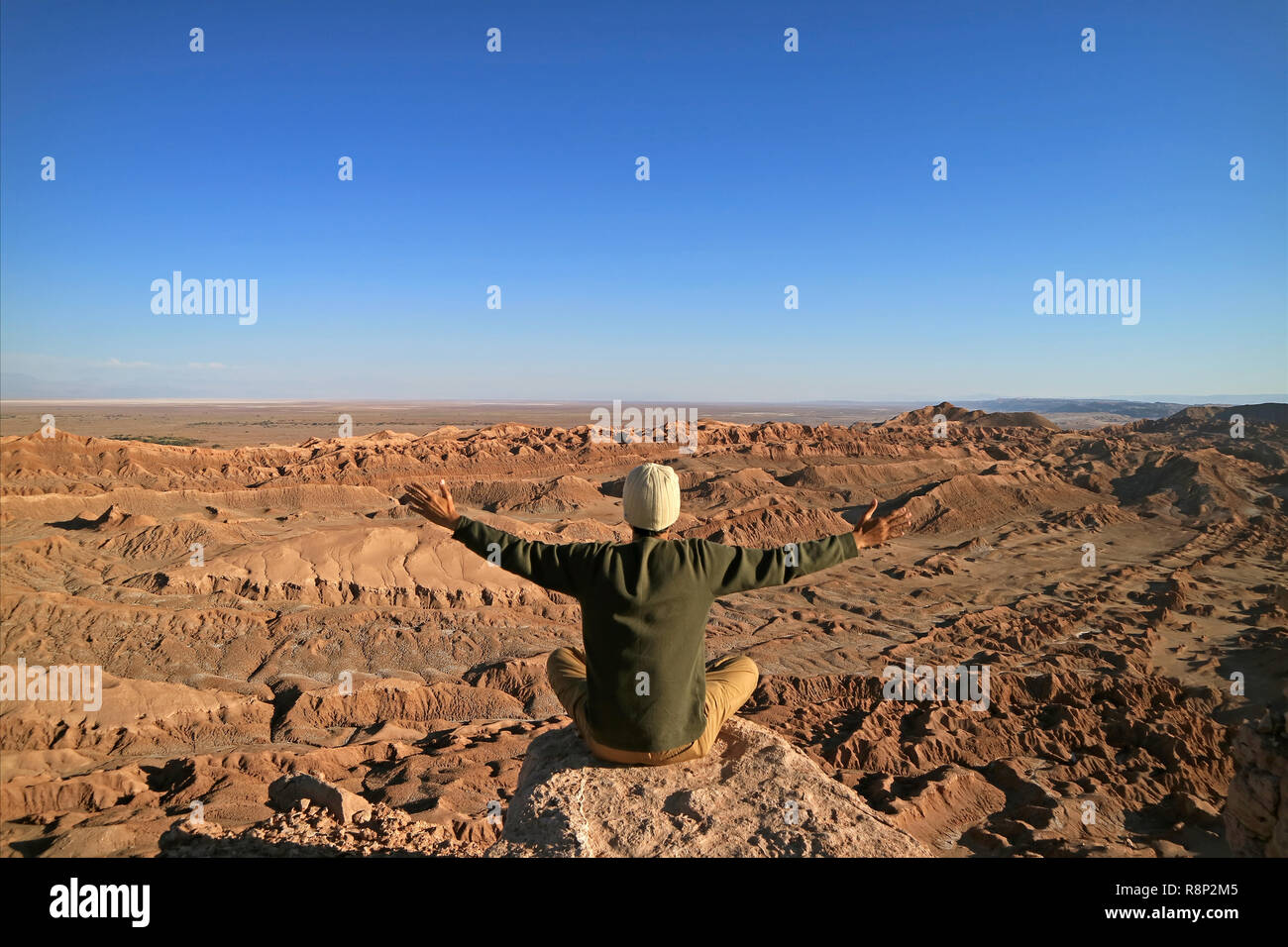 Uomo seduto sulla roccia di bracci di sollevamento di apprezzare la splendida vista della Valle della Luna o Valle de la Luna, il Deserto di Atacama, San Pedro Atacama, Cile Foto Stock