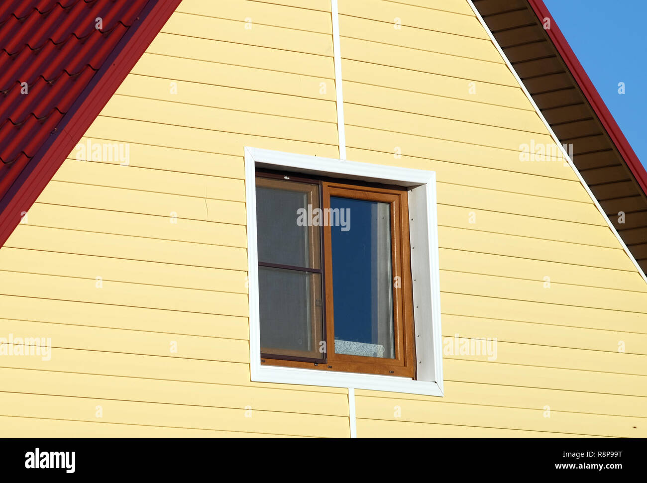 Parete ricoperta con giallo schierata e finestra nella cornice marrone sulla giornata soleggiata vista laterale vista dettagliata Foto Stock