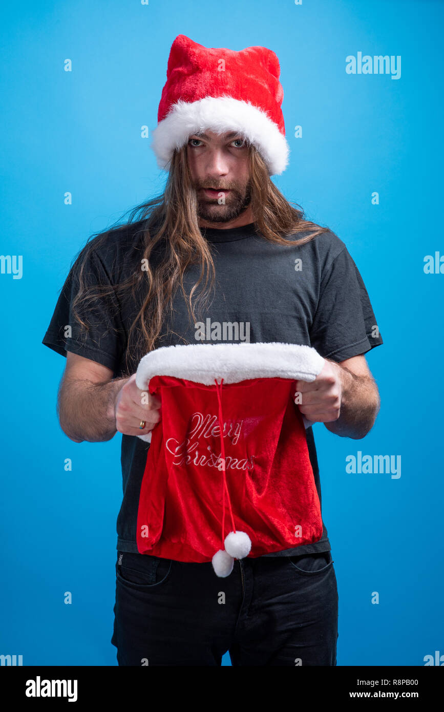 Ritratto o ventola indossando santa hat guardando la telecamera ha stupito con un sacco vuoto. Holiday celebrazione con regali stagionali Foto Stock