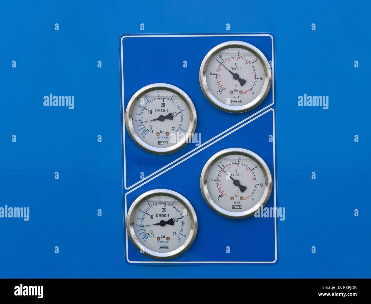 Il gruppo di quattro analogici manometri Bourdon di un impianto di indutrial, sfondo blu Foto Stock