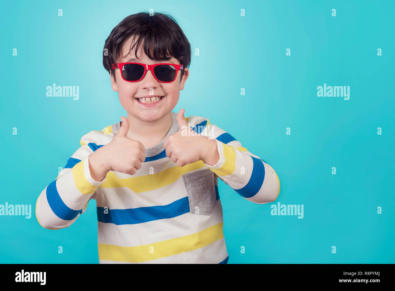 Sorridente Ragazzo con occhiali da sole su sfondo blu Foto Stock