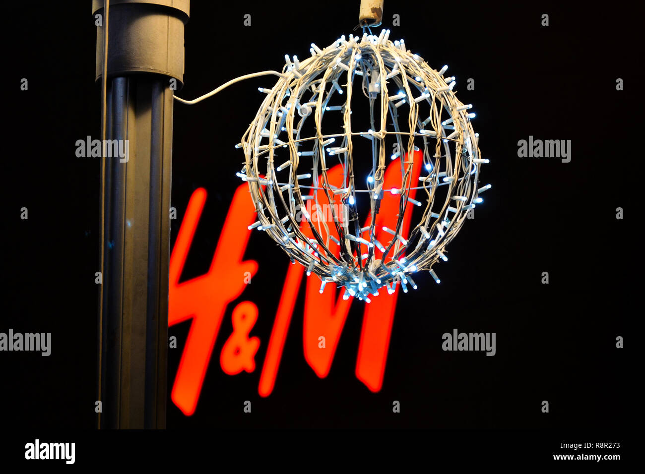 Nsi,Serbia,Dicembre 24,2016:decorative grande palla fatta di luci di Natale di fronte H&M logo da parte di notte sulla strada per le vacanze. Foto Stock
