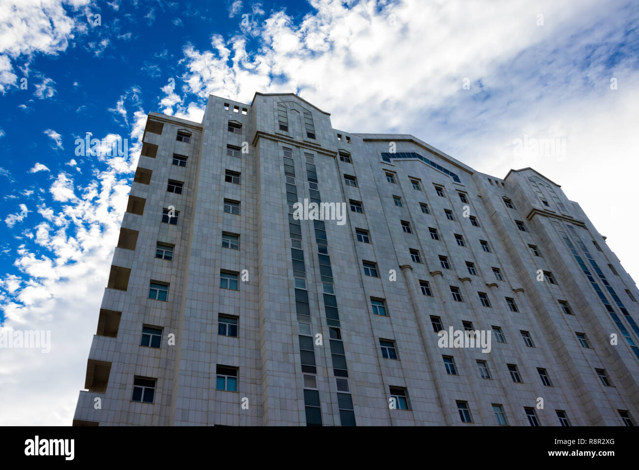 Un bianco residenziale/commerciale moderna torre su un nuvoloso cielo blu sullo sfondo Foto Stock
