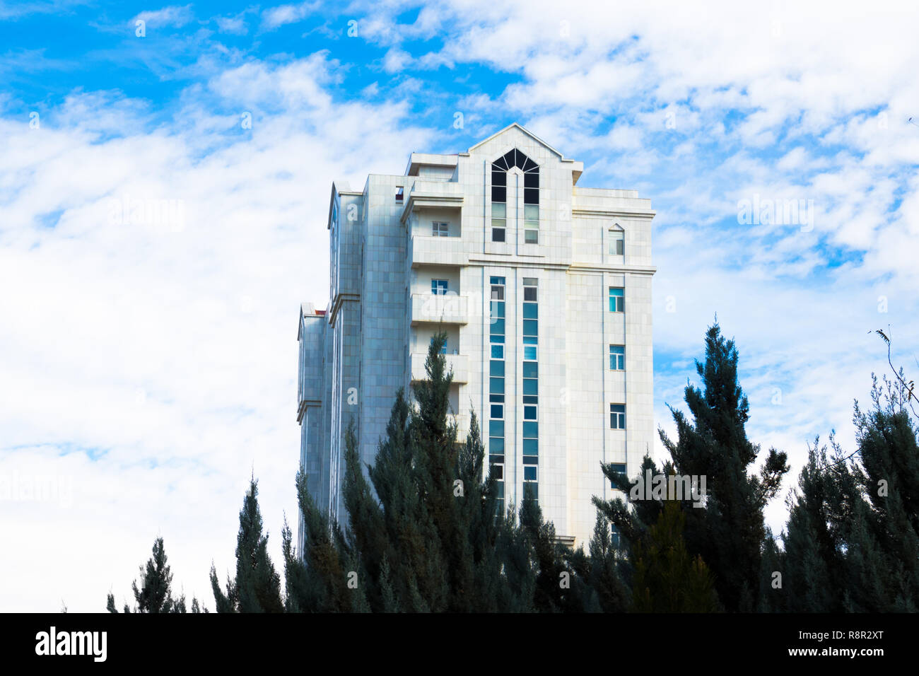 Un bianco residenziale/commerciale moderna torre su un nuvoloso cielo blu sullo sfondo Foto Stock