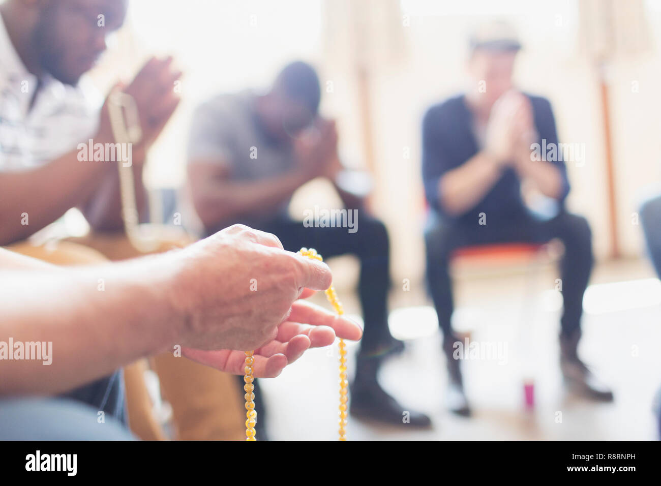 Gli uomini di pregare con rosari in gruppo di preghiera Foto Stock