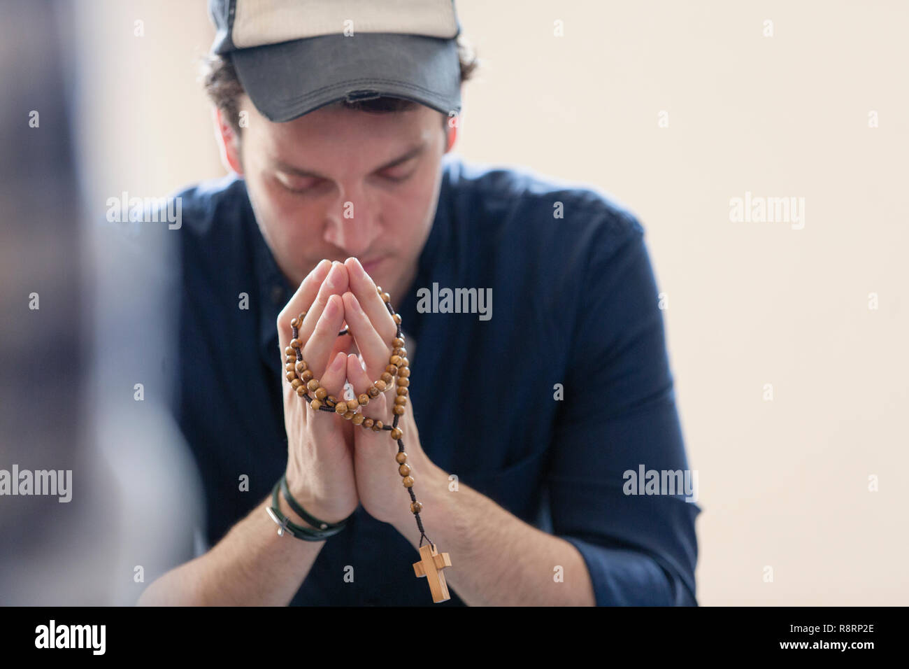 Uomo che prega con il rosario Foto Stock