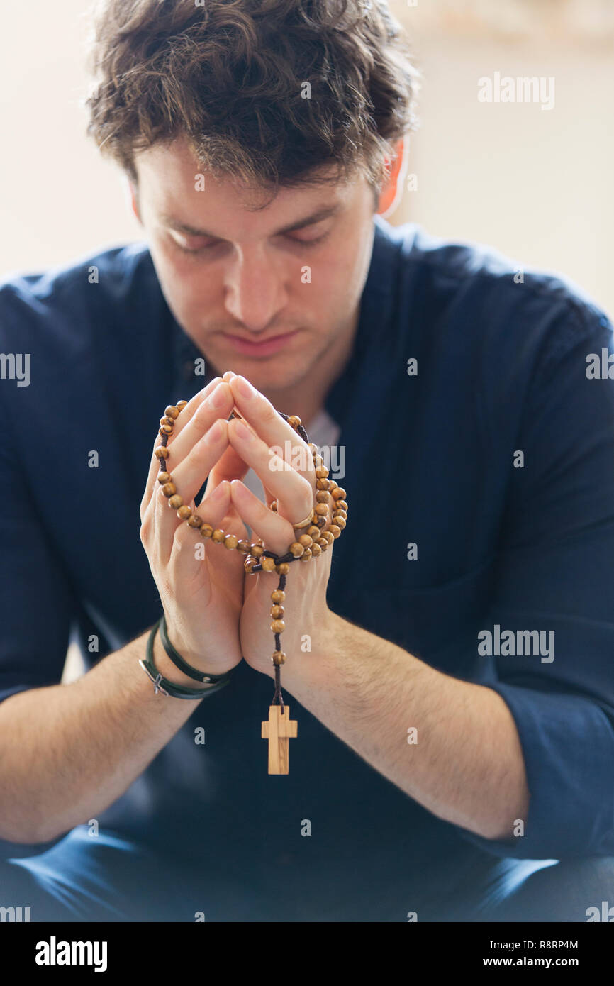 Serena uomo che prega con il rosario Foto Stock