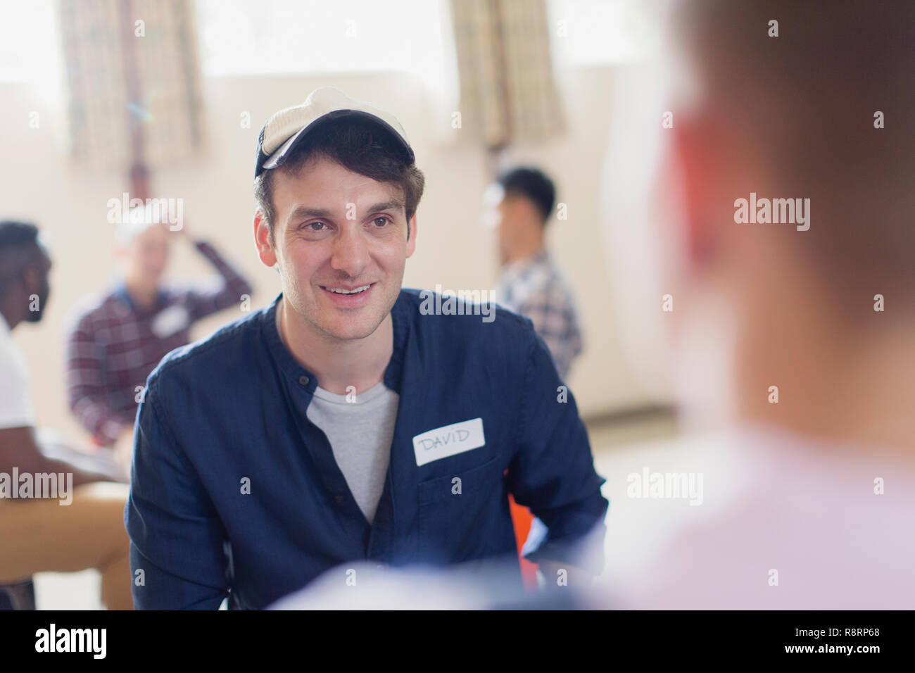 Uomo sorridente in ascolto in terapia di gruppo Foto Stock