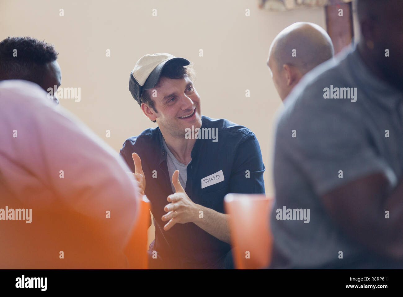 Uomo sorridente parlando in una terapia di gruppo Foto Stock