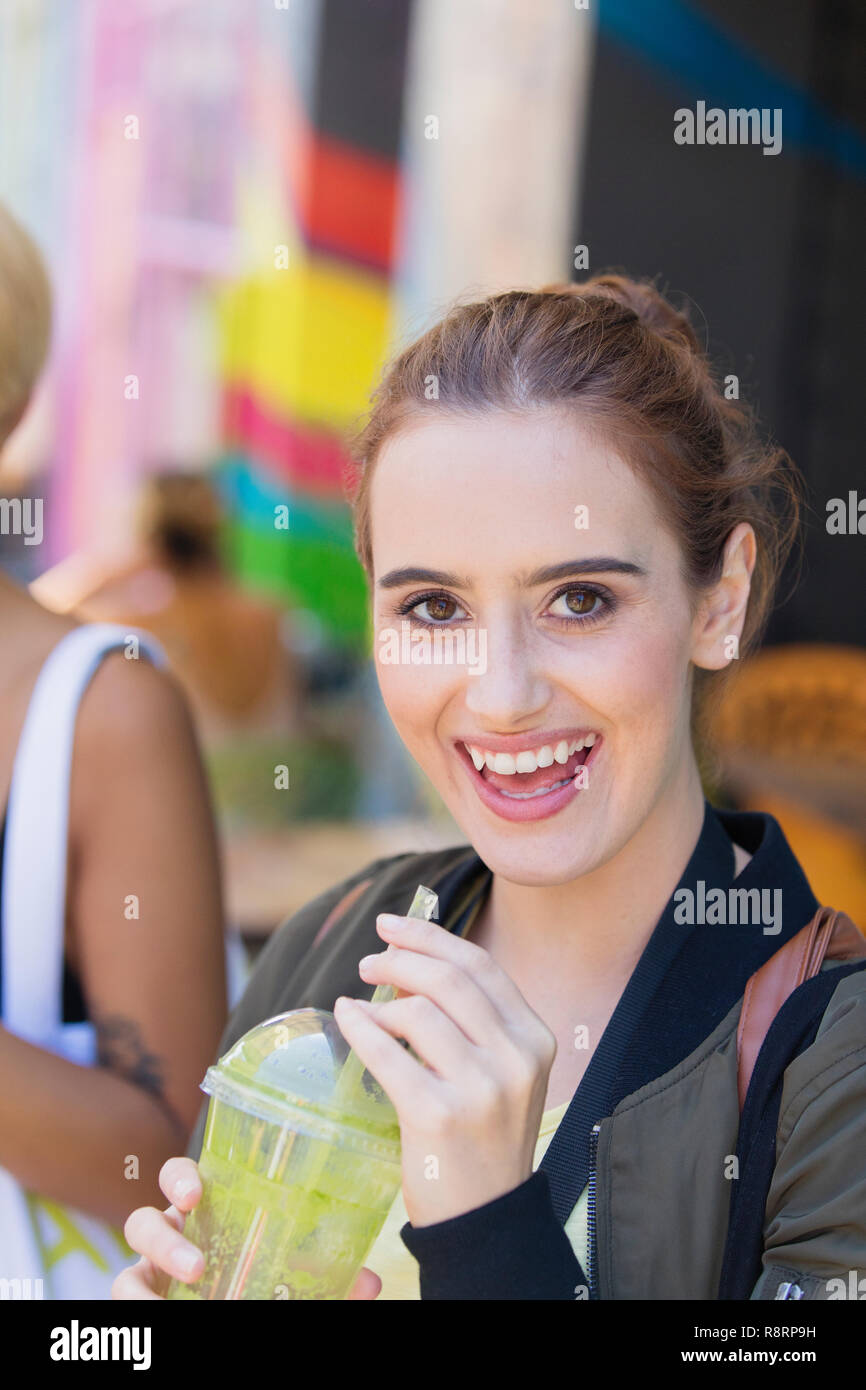 Ritratto felice giovane donna bere frullato verde Foto Stock