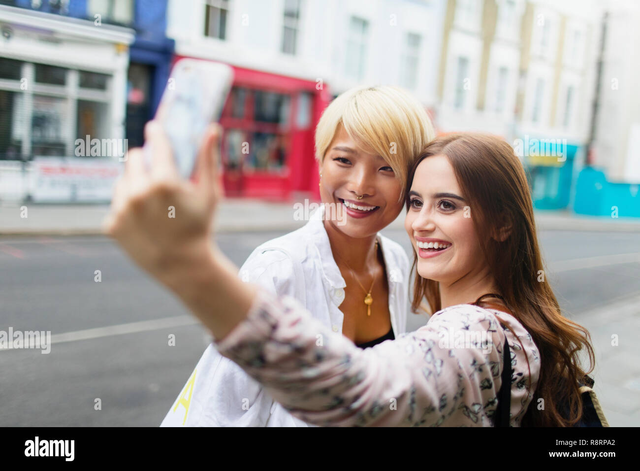 Giovani donne amici prendendo selfie con smart phone su strada urbana Foto Stock