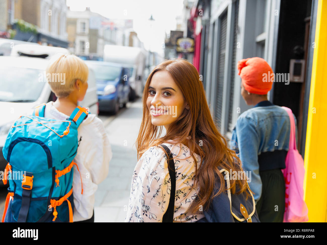 Ritratto sorridente, fiducioso giovane donna con zaino sul marciapiede urbano Foto Stock