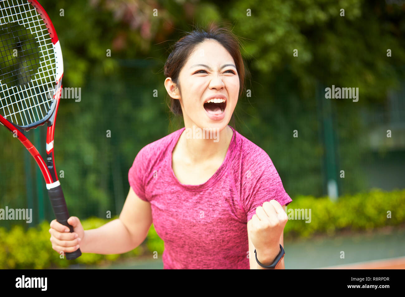 Giovane ragazza asiatica femmina giocatore di tennis in festa dopo il punteggio di un punto Foto Stock