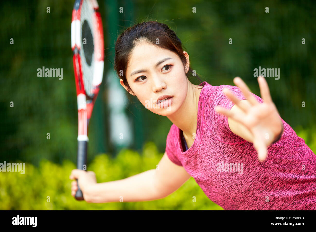 Giovane donna asiatica femmina giocatore di tennis di colpire la palla con diretti Foto Stock