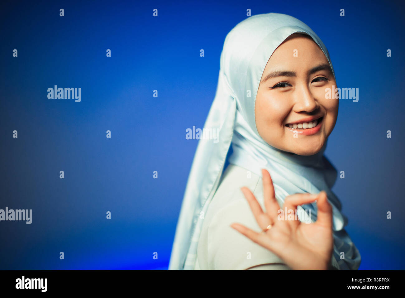 Ritratto sorridente, fiducioso giovane donna in hijab gesticolando OK Foto Stock