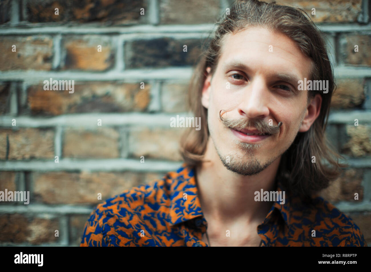 Ritratto sorridente, fiducioso giovane maschio hipster con i baffi Foto Stock