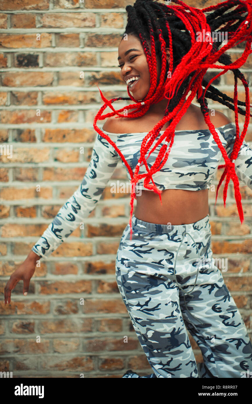 Spensierato giovane donna in Abbigliamento camouflage dancing contro un muro di mattoni Foto Stock