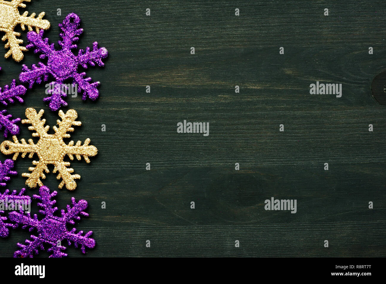 Giallo e viola i fiocchi di neve come decorazione di Natale sul legno scuro dello sfondo. Copia dello spazio. Foto Stock