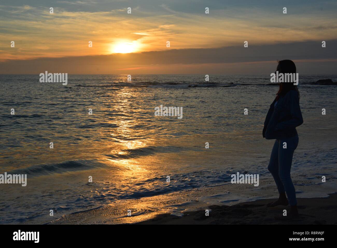 Silhouette di una giovane donna guardando il tramonto sull'oceano. Laguna Beach, California, Stati Uniti d'America. Foto Stock