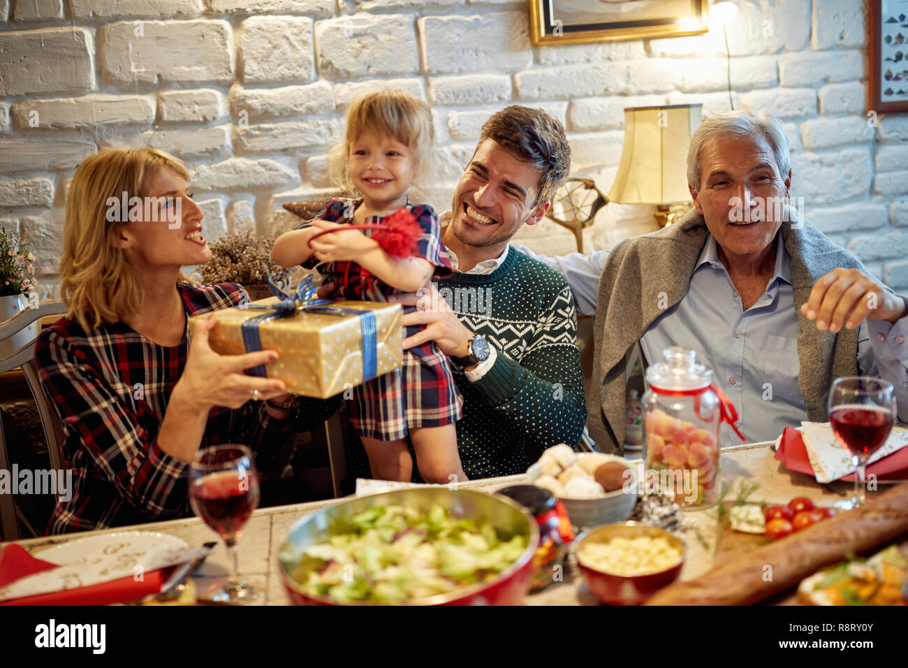 La famiglia felice sono a cena a casa. Celebrazione di vacanze e di Exchange presente insieme Foto Stock