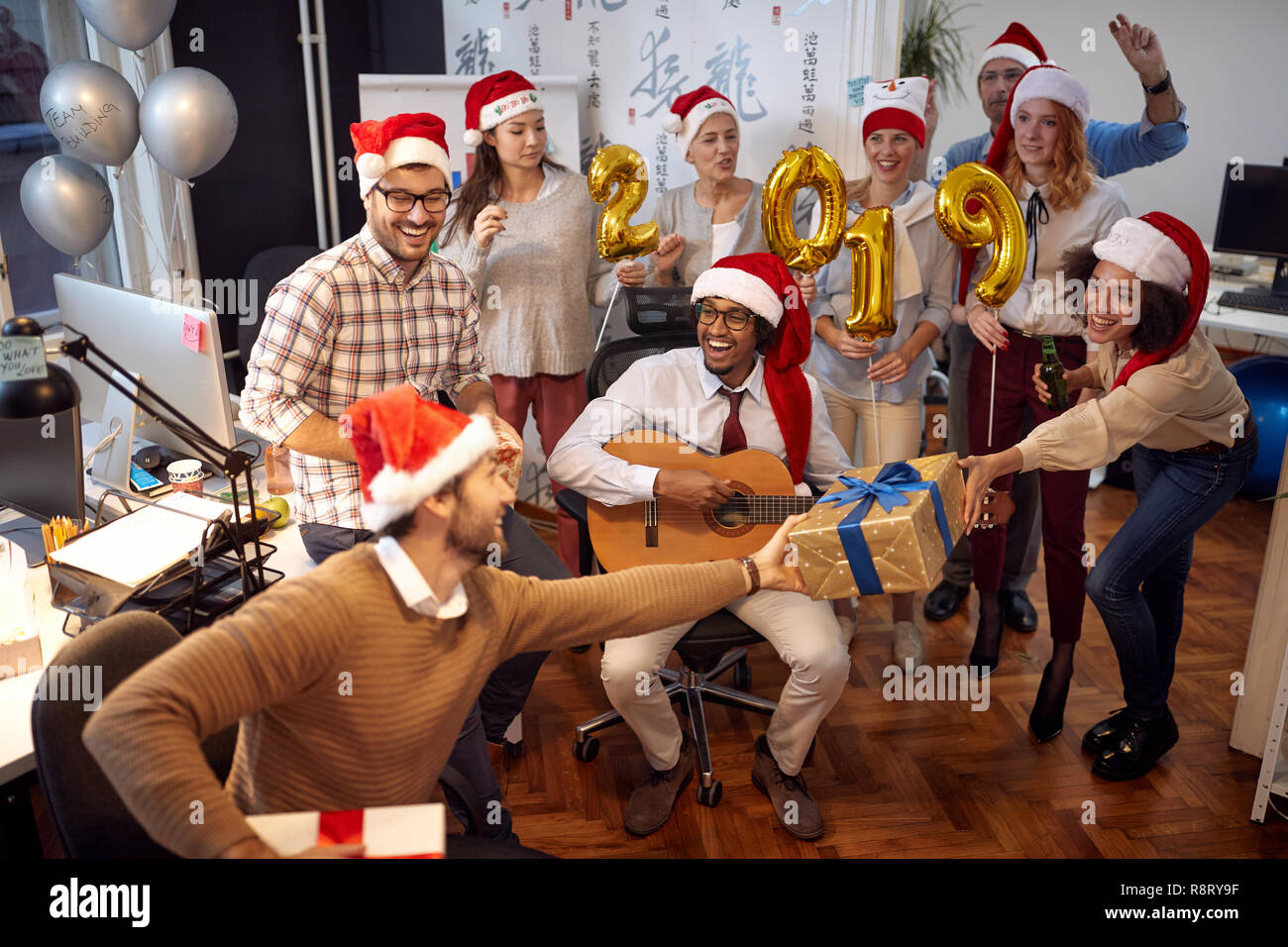 Sorridente lavoratori aziendali divertirsi in Santa hat alla festa di Natale e scambio di doni in office Foto Stock