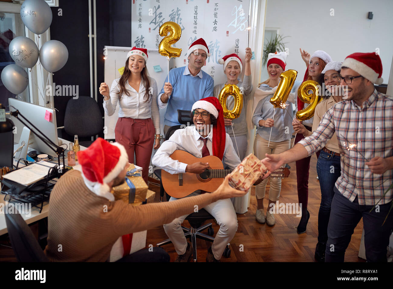 Happy business team hanno divertimento e balli in Santa hat a Xmas Party e scambio di doni in office Foto Stock