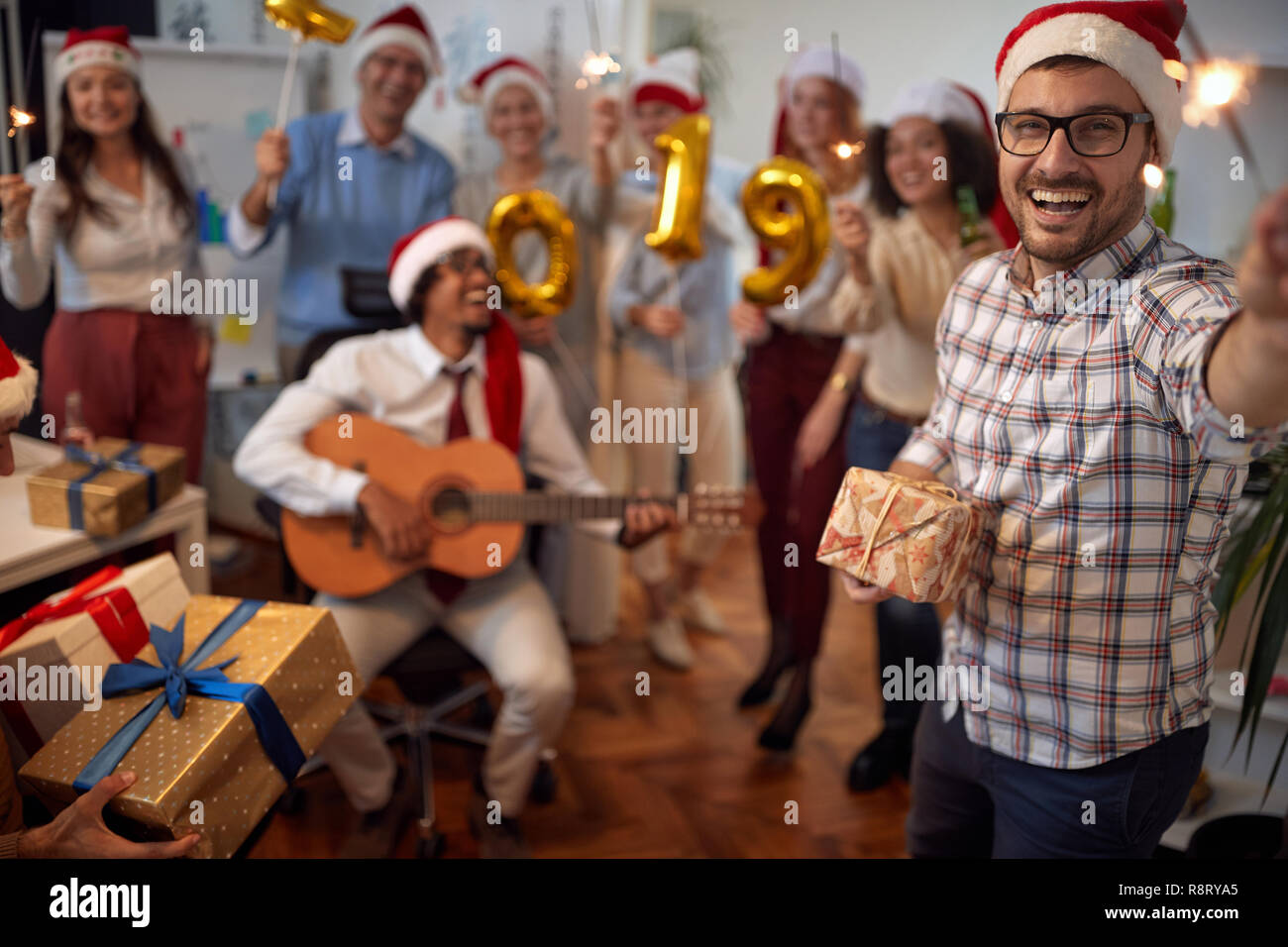 Sorridente business man divertirsi in Santa hat a Xmas Party con i suoi colleghi in ufficio Foto Stock