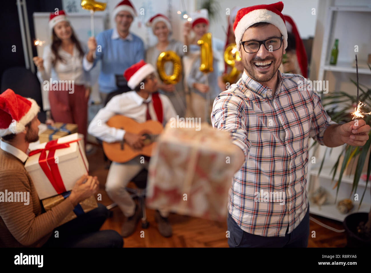 Happy business man divertirsi in Santa hat a Xmas Party con i suoi colleghi in ufficio Foto Stock