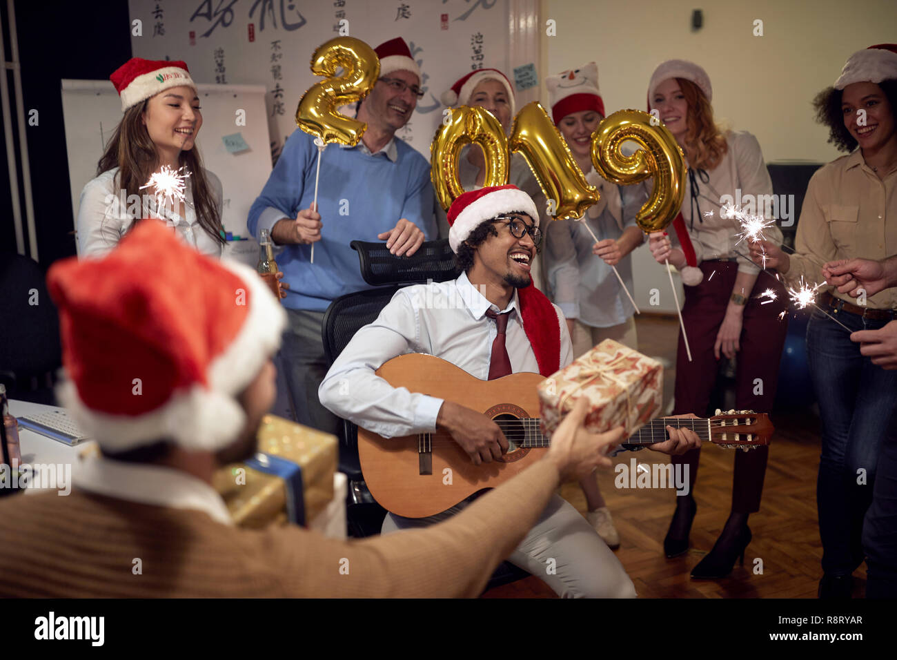 Happy business gruppo di persone in Santa hat avendo divertimento per celebrità festa di Natale con la canzone in ufficio. Foto Stock