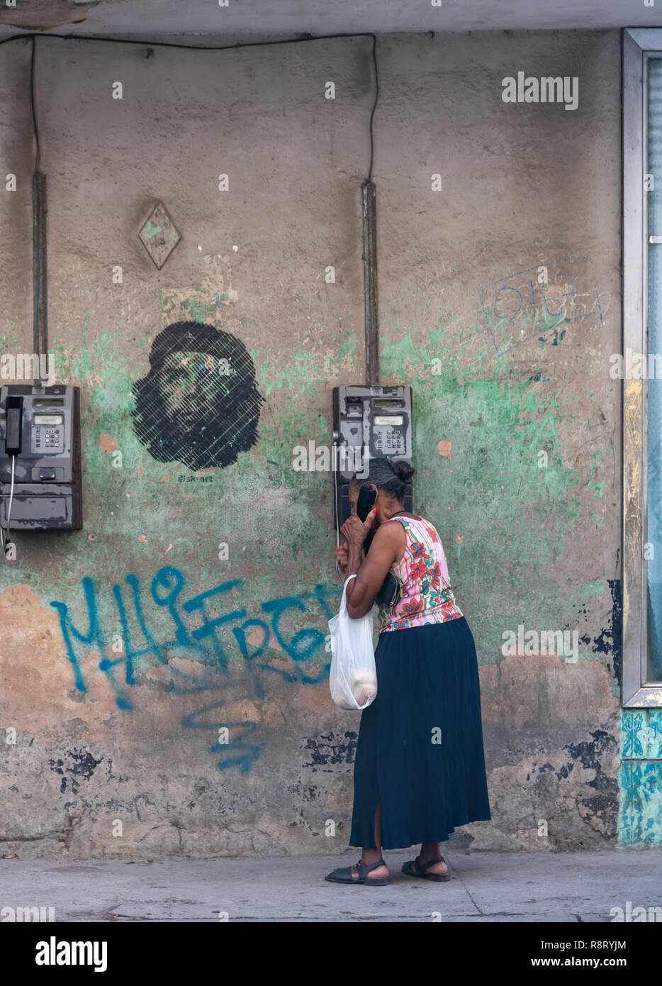 Donna cubana su un telefono a gettoni a l'Avana, Cuba. Un immagine iconica di Che Guevara appare al di sopra di lei - come se un discorso bolla. Foto Stock